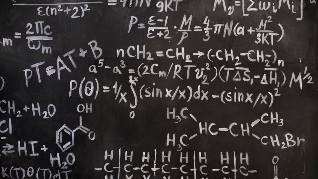 Dense mathematical and chemical formulas chalked on a blackboard
