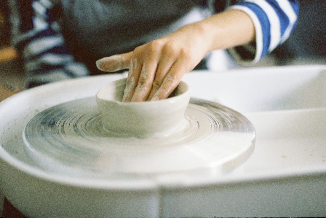 Hands shaping clay on a pottery wheel